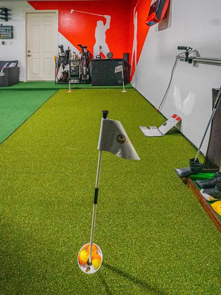 Indoor putting green with a flag and cup at the Eagle Quest Golf studio in west Houston